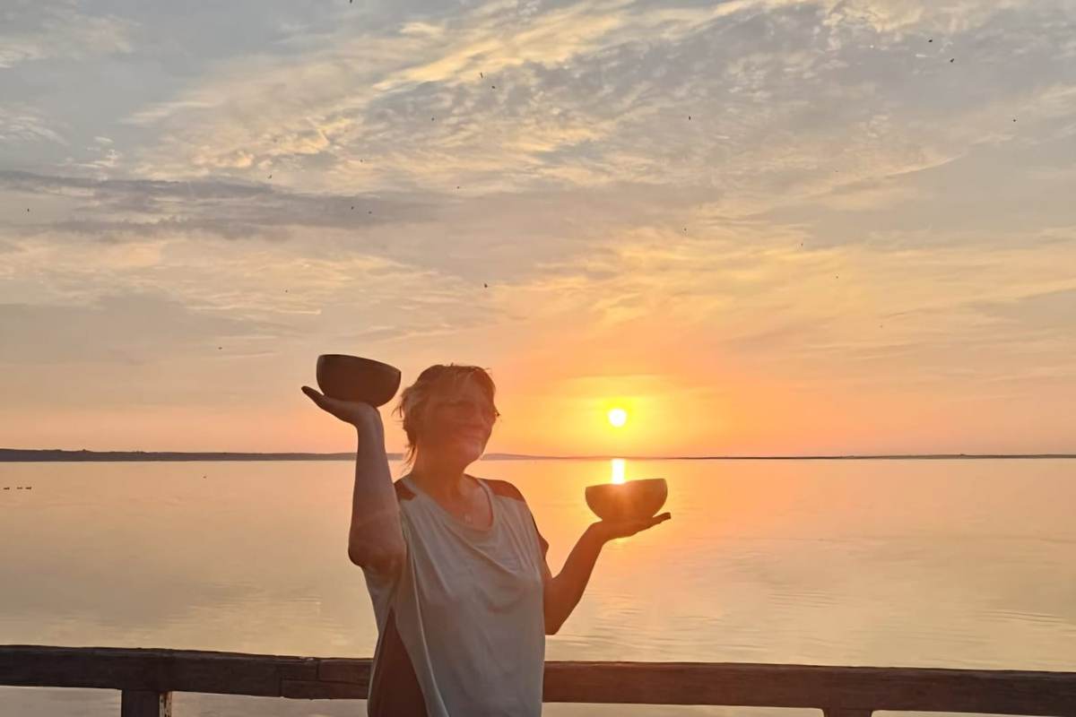 Ina mit zwei Klangschalen im Sonnenuntergang